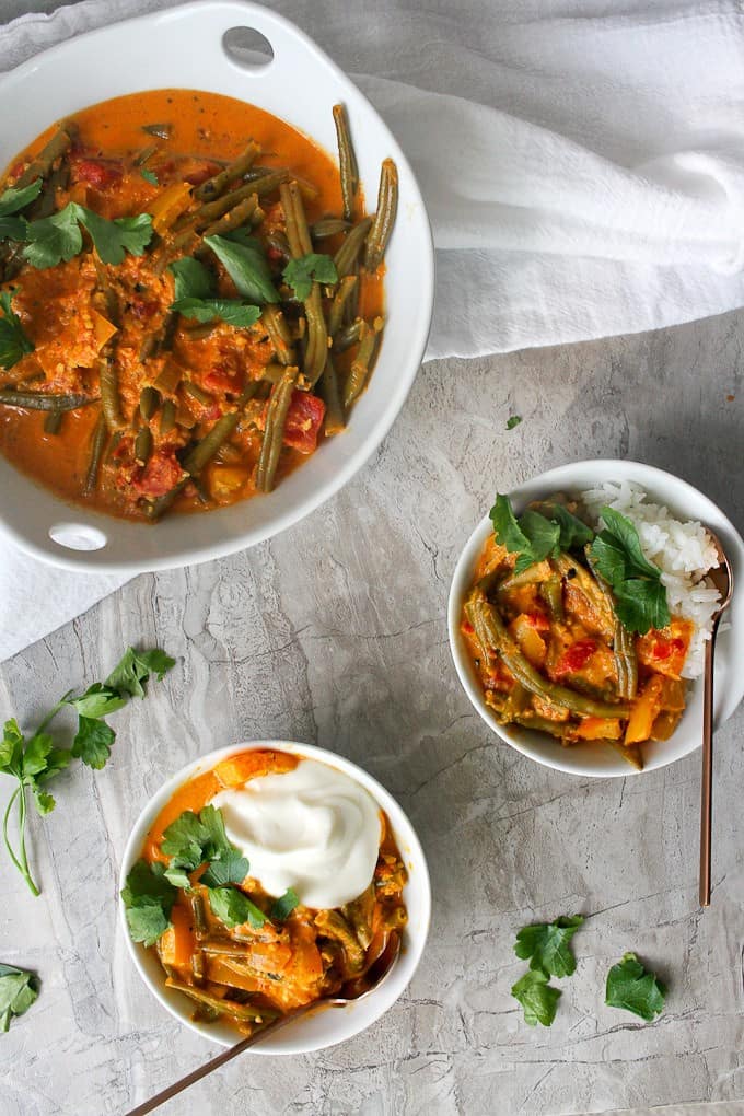 Vegetable korma in serving dishes with yogurt and with rice