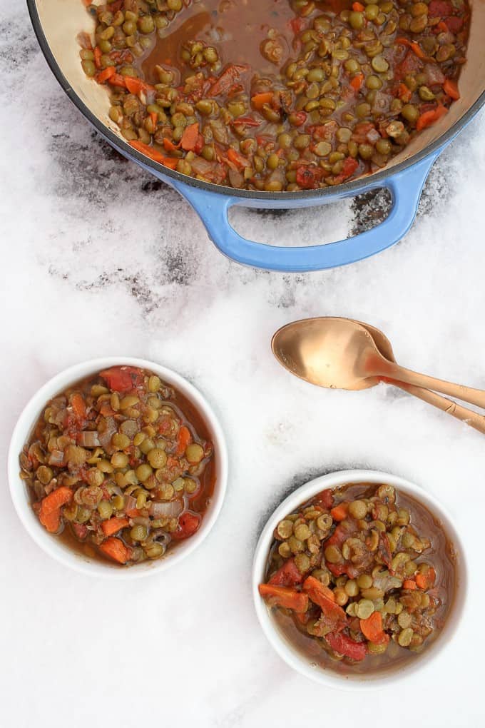 Vegan split pea soup in a pot and bowls, all sitting in the snow