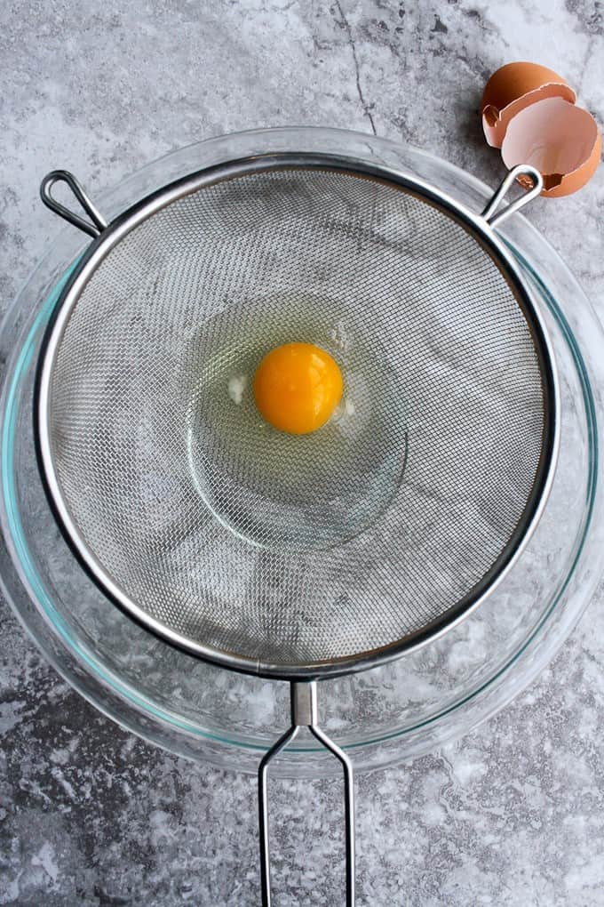 straining an egg in a mesh sieve