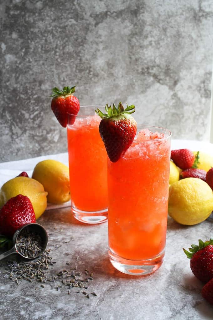 strawberry lemonade in glasses with lavender petals, strawberries, and lemons