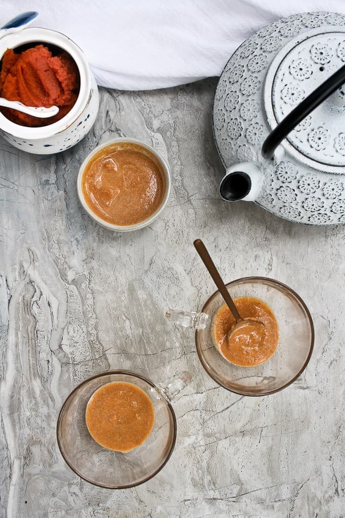 Pumpkin puree mixture in glass teacups  next to teapot.