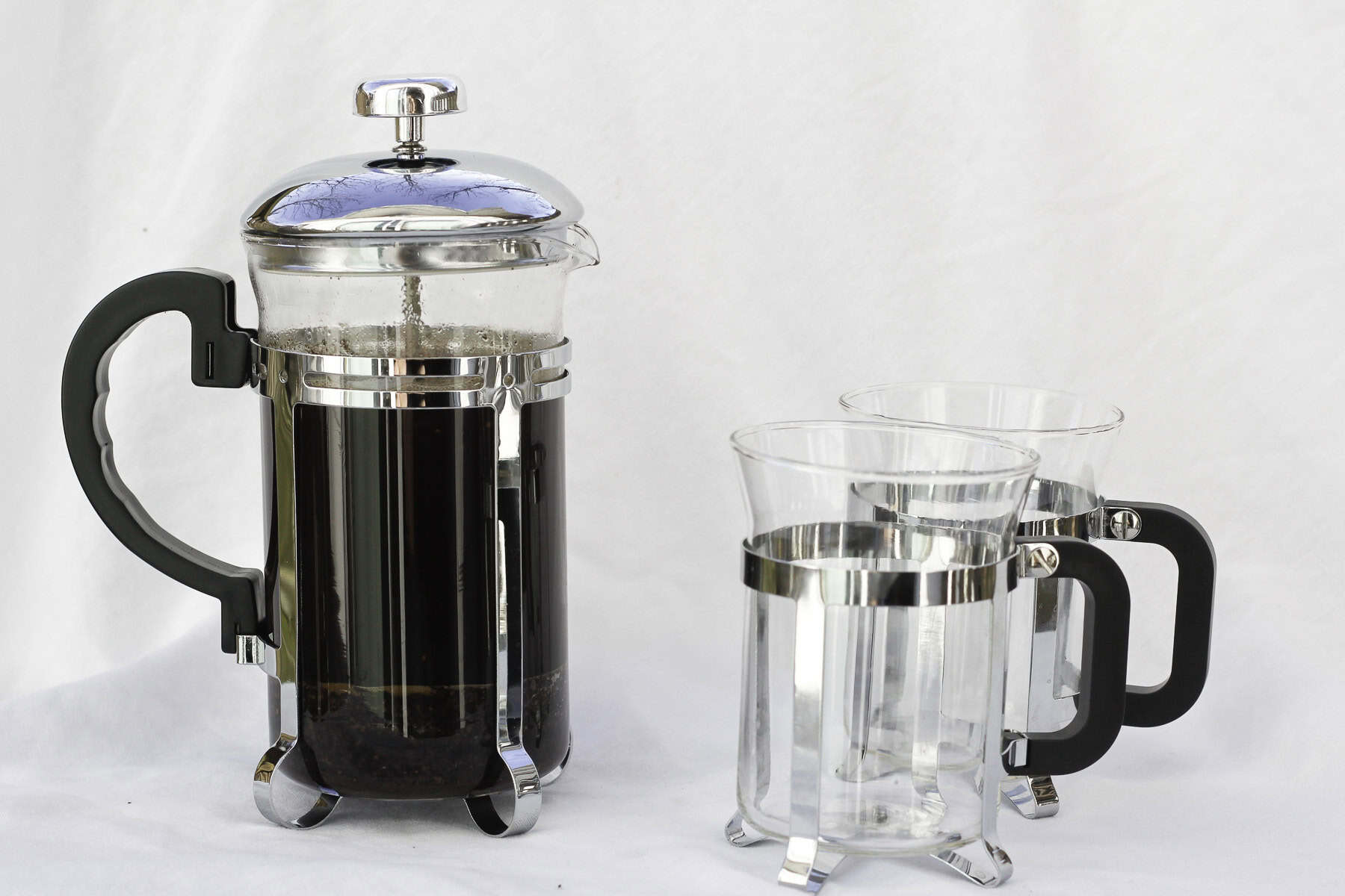 French press with coffee and two empty mugs.