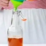 pouring kombucha into a bottle