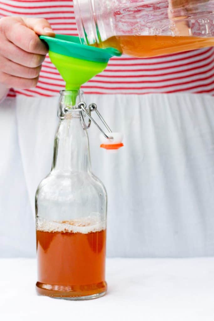 pouring kombucha into a bottle