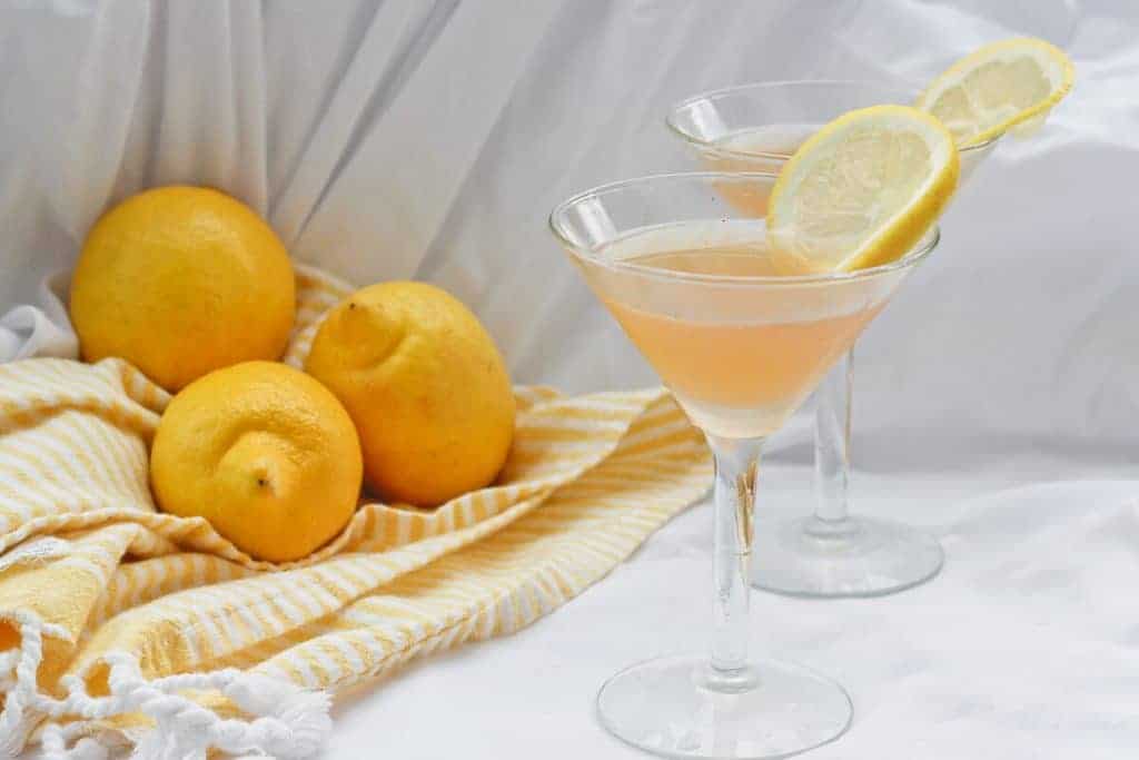 Bourbon Sour with Lavender in 2 Martini Glasses, lemon slices on the glass, lemons in background