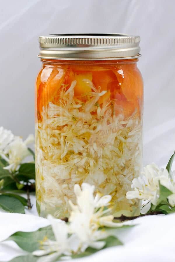 Honeysuckle flowers infusing vodka in a mason jar.