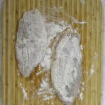 flour dusted fish on a cutting board.