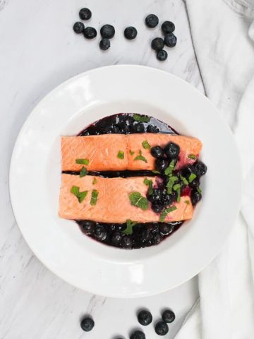 This Poached Salmon with Blueberry Sauce is made with decadent king salmon poached in spiced white wine, and served with an easy blueberry sauce. champagne-tastes.com #ad