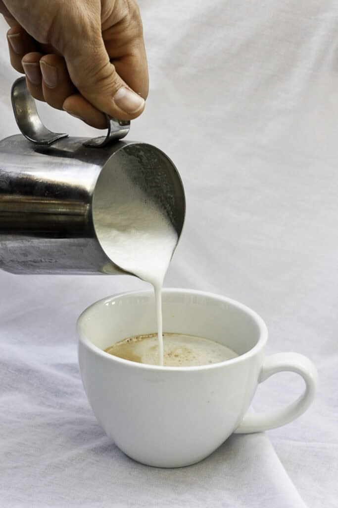 Pouring frothed eggnog into the espresso.