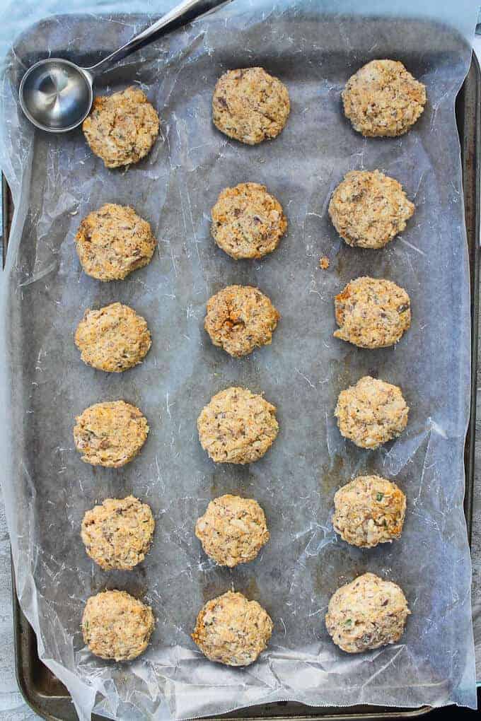 Unbaked sardine fish cakes on a baking sheet with a scoop.