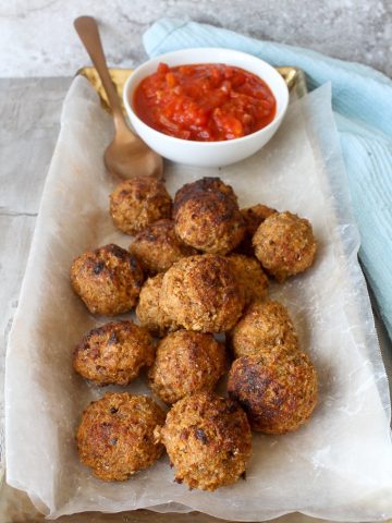 Albondigas de pescado (fish balls / fish meatballs) on a serving tray with tomato sauce