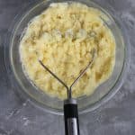 mashing goat cheese mashed potatoes with a potato masher.