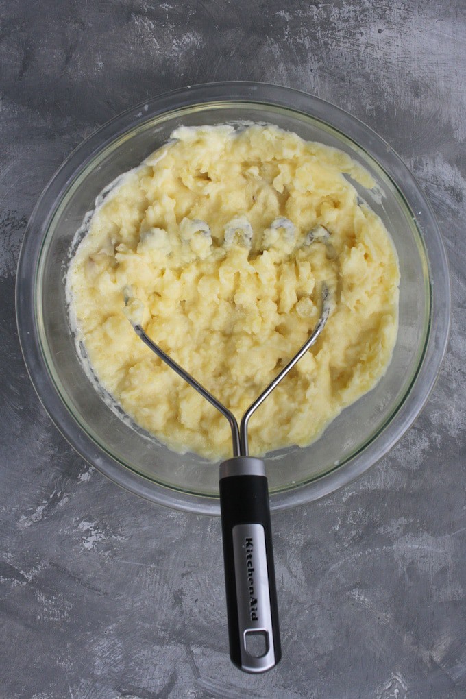 mashing goat cheese mashed potatoes with a potato masher