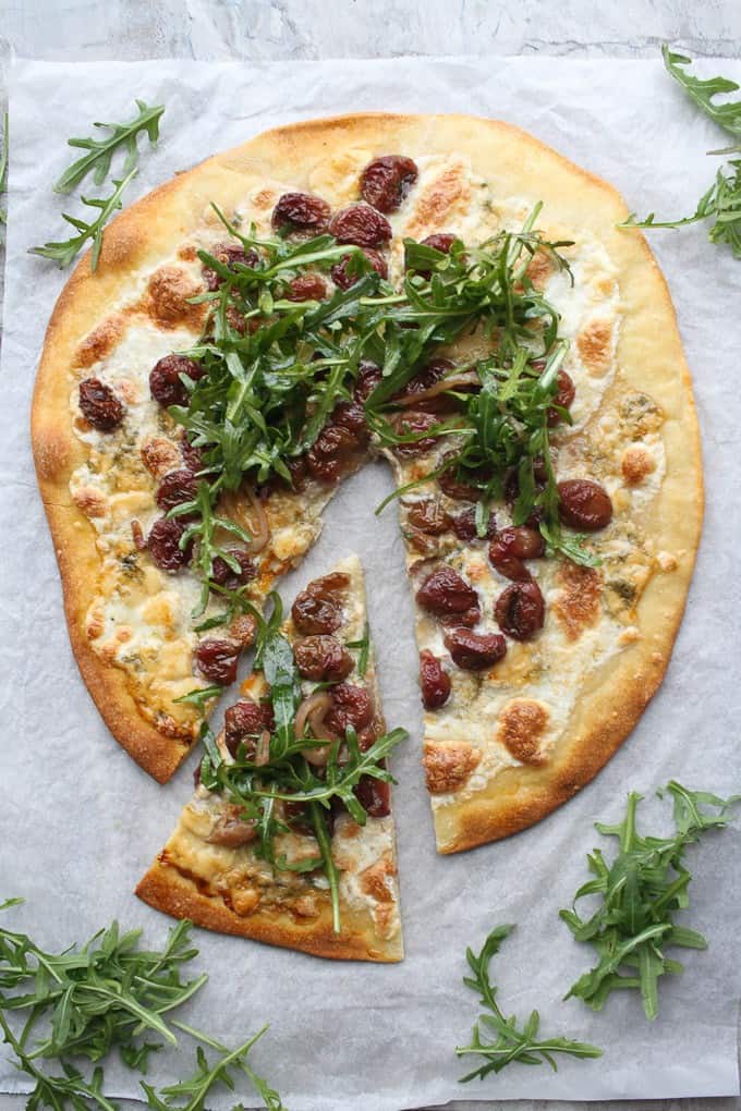 Arugula pizza with one slice cut out and extra arugula