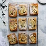 apple tarts on a cooling rack surrounded by forks and plates