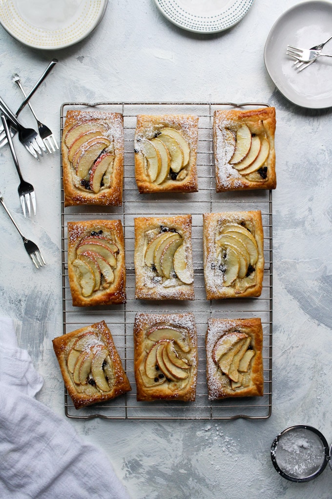 apple tarts on a cooling rack surrounded by forks and plates.