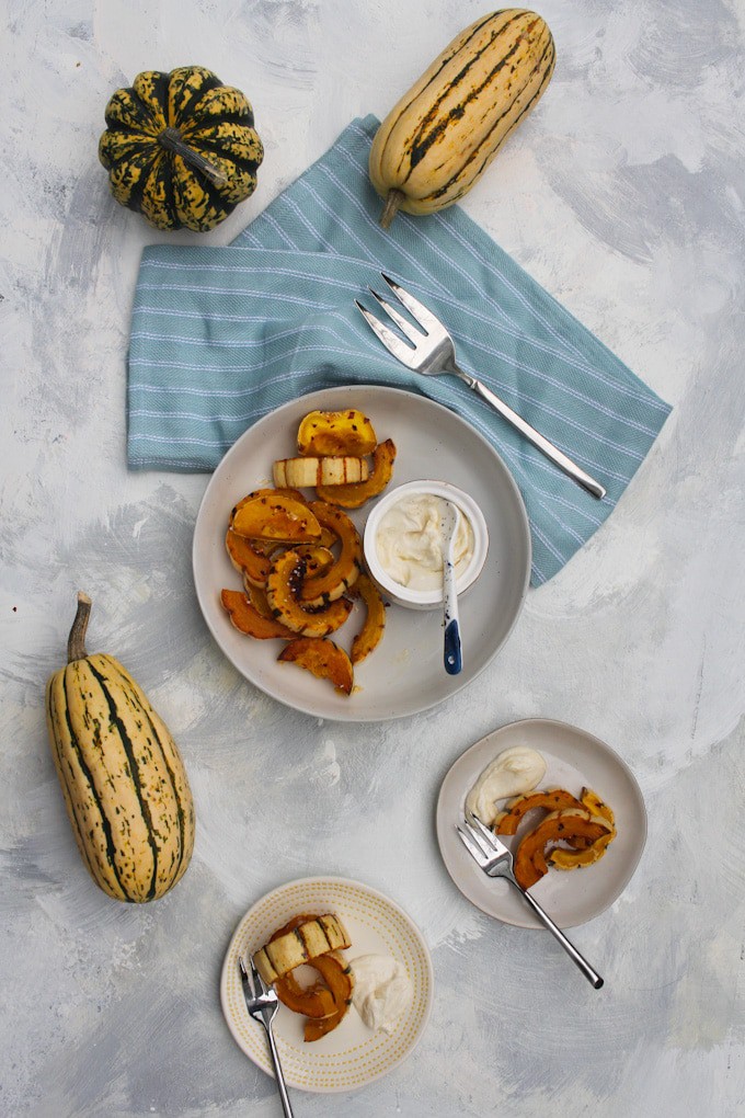 roasted delicata squash in a serving bowl with tahini yogurt sauce on the side