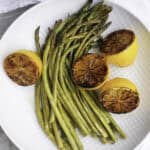 roasted asparagus with charred lemons on plate.