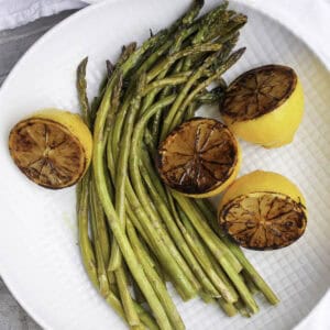 roasted asparagus with charred lemons on plate.