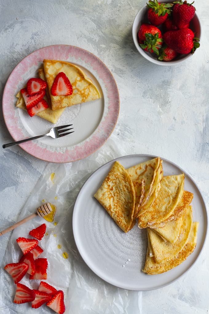 french crepe recipe: basic crepes on a serving dish with strawberries