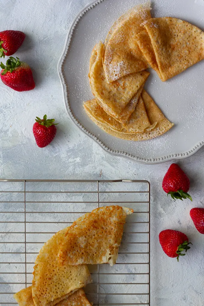 moving vegan crepes from a cooling rack to a serving tray