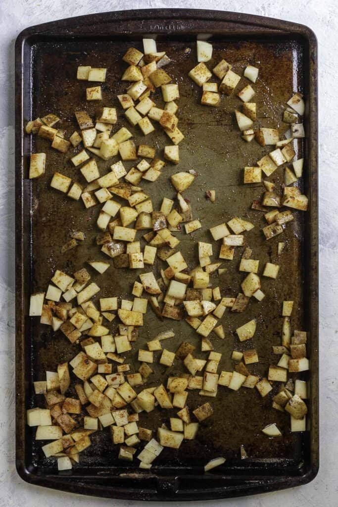 uncooked seasoned potatoes on a baking sheet.