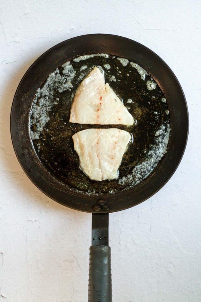 uncooked rockfish in pan with butter.