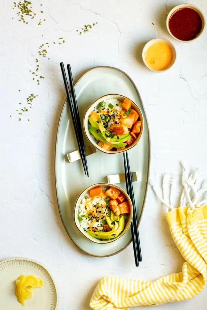 spicy salmon poke bowls on a serving tray with chopsticks