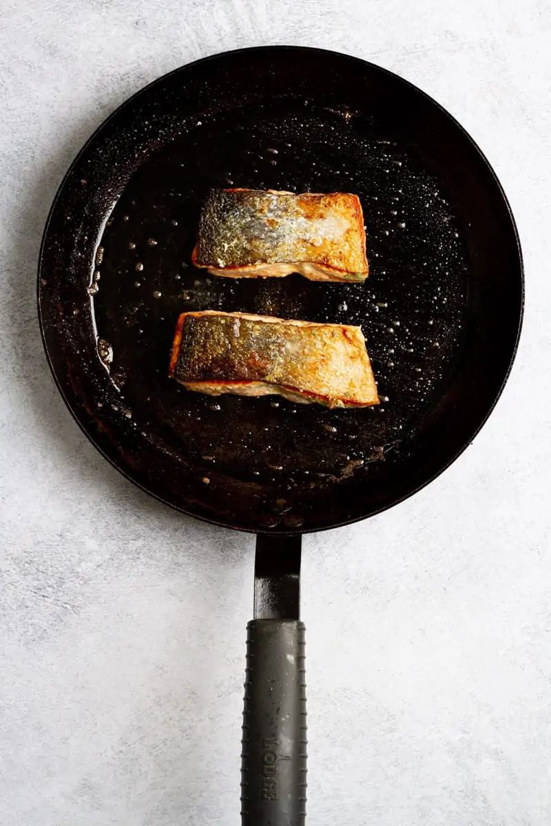 Salmon cooking in pan skin-side up.