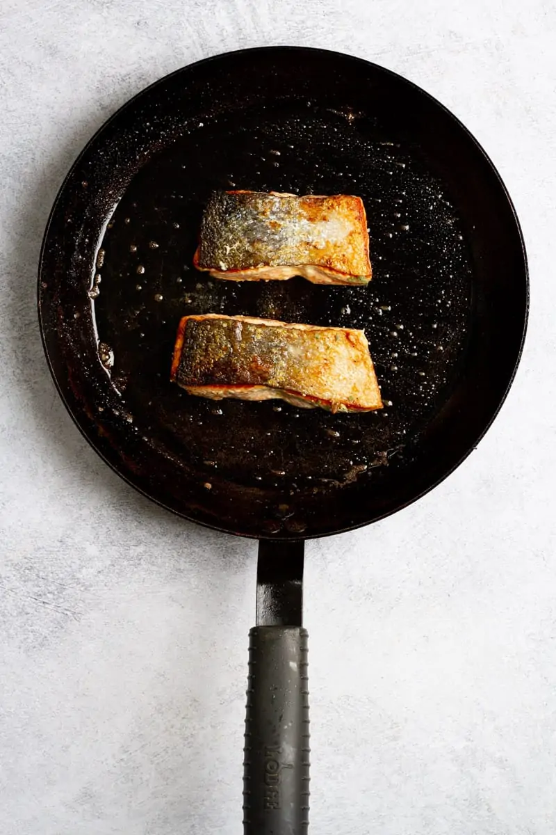 Salmon skin-side up in skillet.