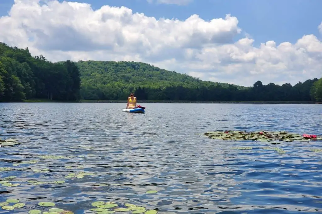 Person paddling on board in middle of lake.