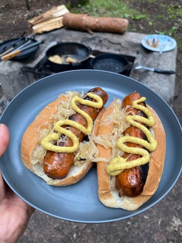 Campfire beer bratwurst on hot dog buns with mustard.