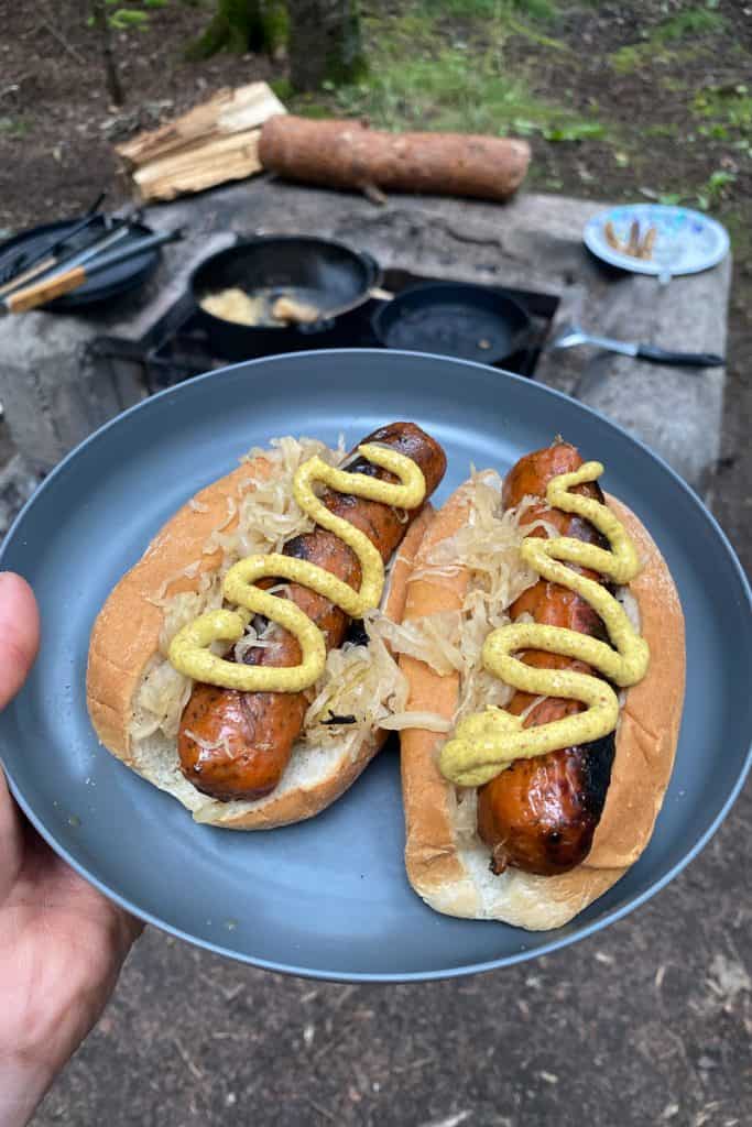 Campfire beer bratwurst on hot dog buns with mustard.