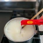 Eggnog on stovetop with thermometer reading 160-degrees F.
