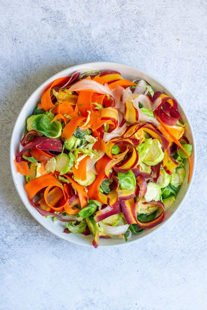 bowl with carrots, sprouts and fruit tossed together.