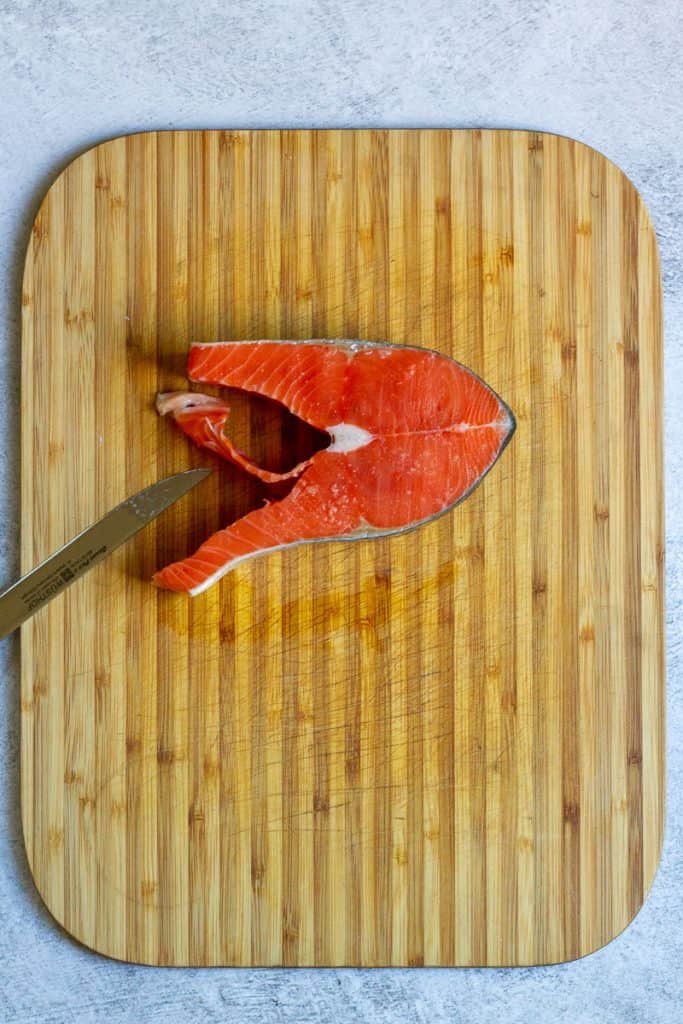 To debone a salmon steak, make a cut from one side.