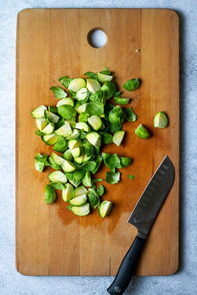 Quartered brussels sprouts on a cutting board.
