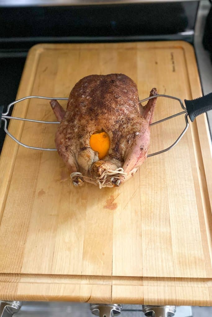duck on a cutting board with poultry lifters inserted.