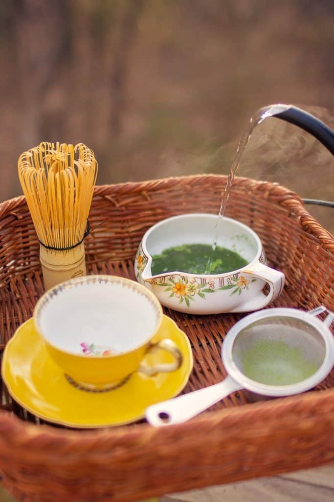 teacup, sieve, whisk and matcha in bowl