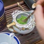 stirring matcha in sieve over small bowl