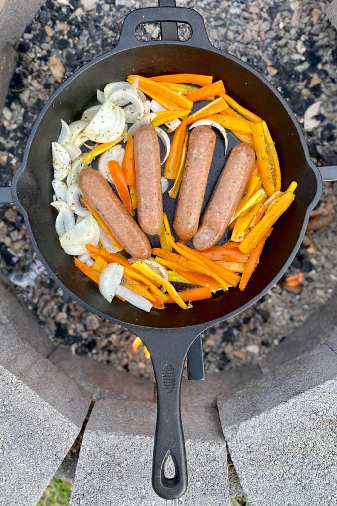 Sausages, onions and peppers in cast-iron pan.