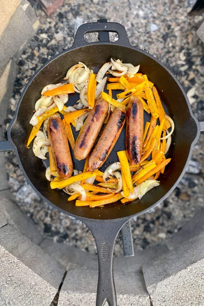 Cooked onions and peppers and brats in cast-iron pan.