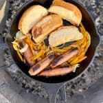 Toasted buns in cast-iron pan along with sausages and onions and peppers.