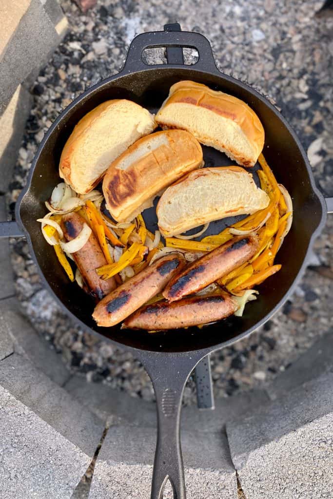 Toasted buns in cast-iron pan along with sausages and onions and peppers.