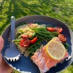 Salmon with couscous, tomatoes, beans, and lemon on plate.