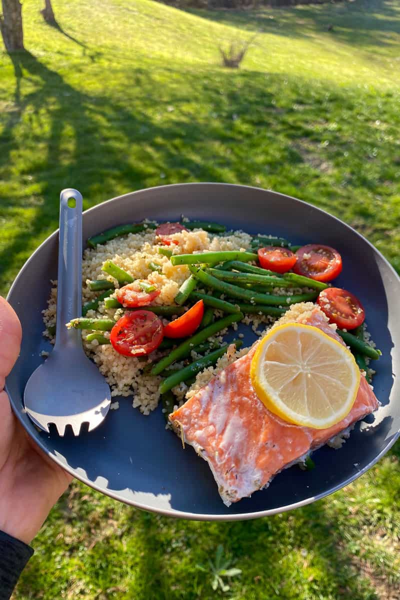 Salmon with couscous, tomatoes, beans, and lemon on plate.