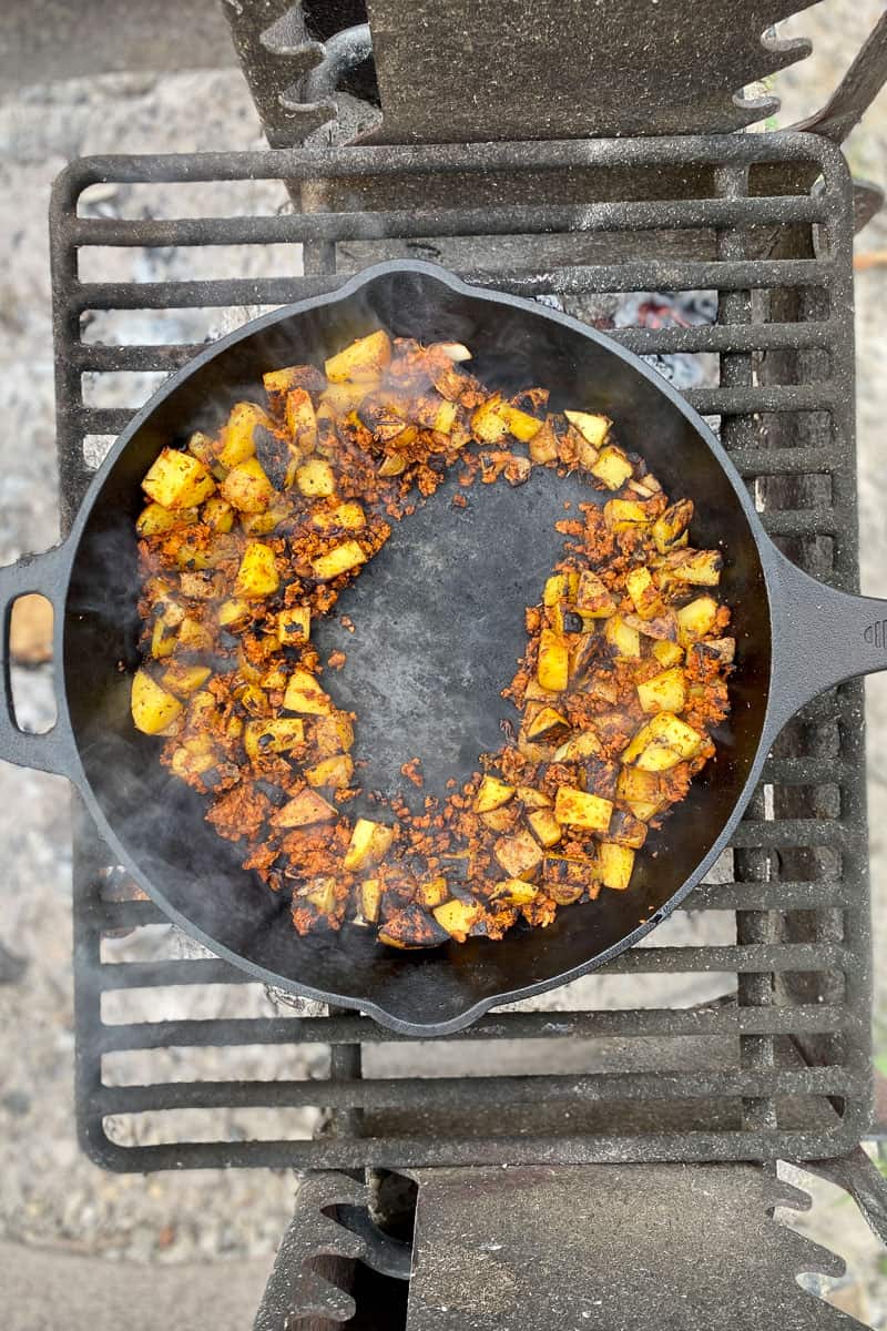 Cooked chorizo and potatoes with space left in the middle of skillet.
