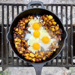 Eggs in middle of skillet surrounded by potatoes and chorizo.