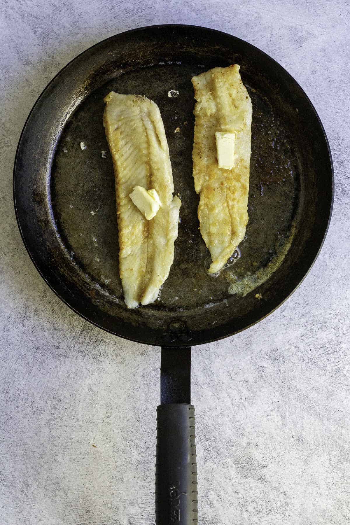 hake in pan, topped with butter.