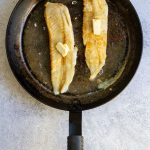 hake with butter in a pan.